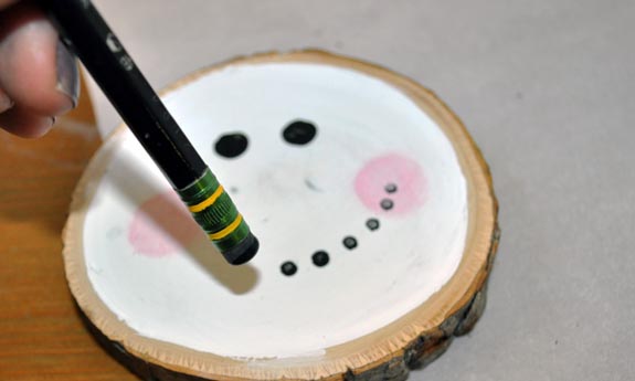 Painting a snowman face with a pencil